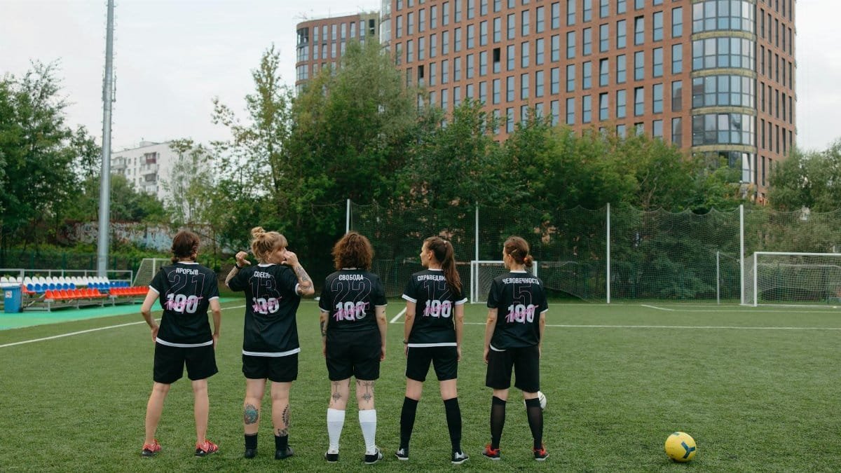 Back view of a women's soccer team preparing for match on an urban soccer field.