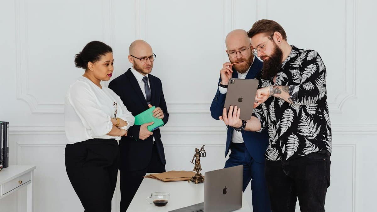 Diverse business team in a modern office discussing strategy using a tablet.