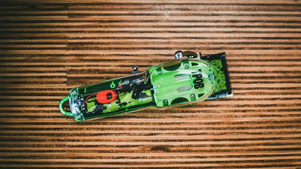 Detailed view of a transparent green electric hair trimmer placed on a wooden surface.