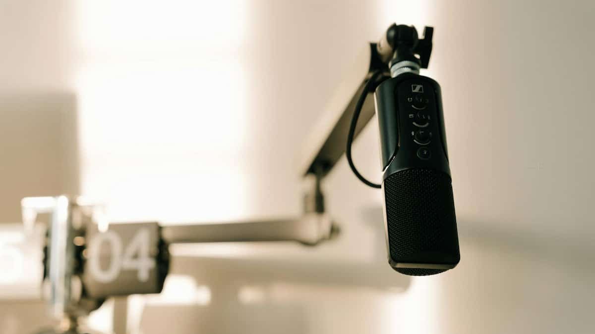 A sleek professional microphone on a boom arm in a minimalist studio.