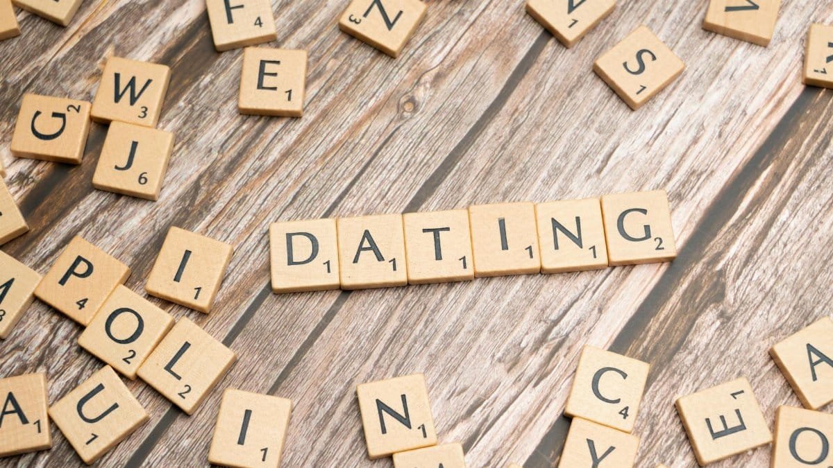 Scrabble tiles forming 'Dating' on a wooden background, representing relationships.