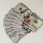 Crisp US hundred dollar bills fanned out on a clean white surface, representing wealth and finance.