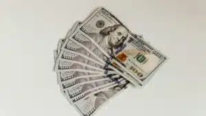 Crisp US hundred dollar bills fanned out on a clean white surface, representing wealth and finance.