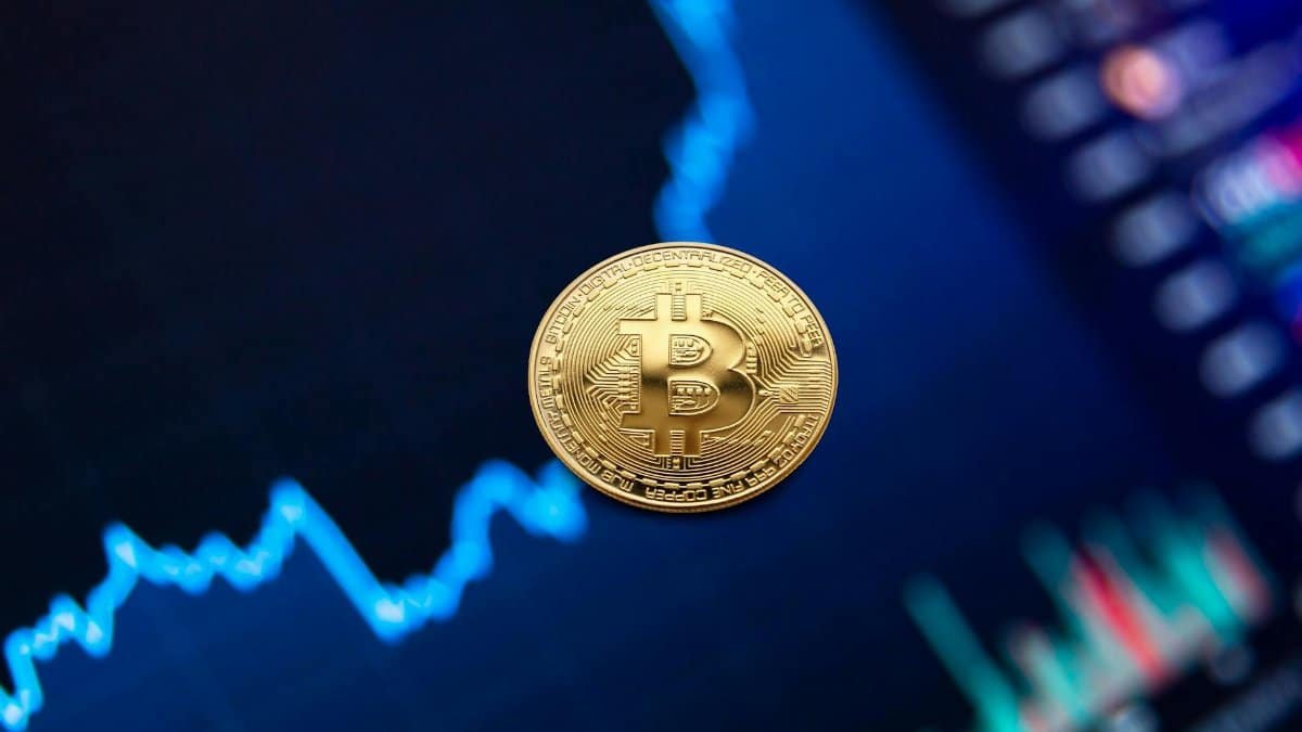 A gold Bitcoin coin against a backdrop of a digital financial chart, symbolizing cryptocurrency trading.