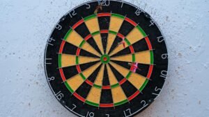 Vibrant dartboard against textured wall with darts on bullseye, symbolizing precision.