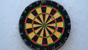Vibrant dartboard against textured wall with darts on bullseye, symbolizing precision.