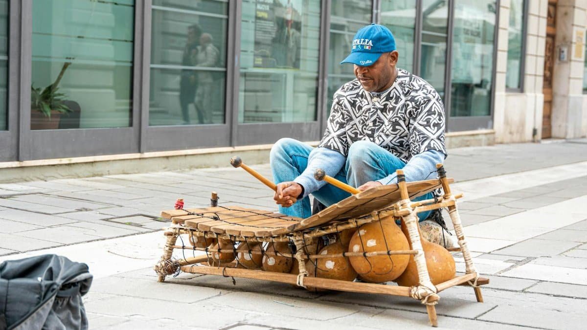 A man playing a traditional xylophone on a city street creates a vibrant urban scene.