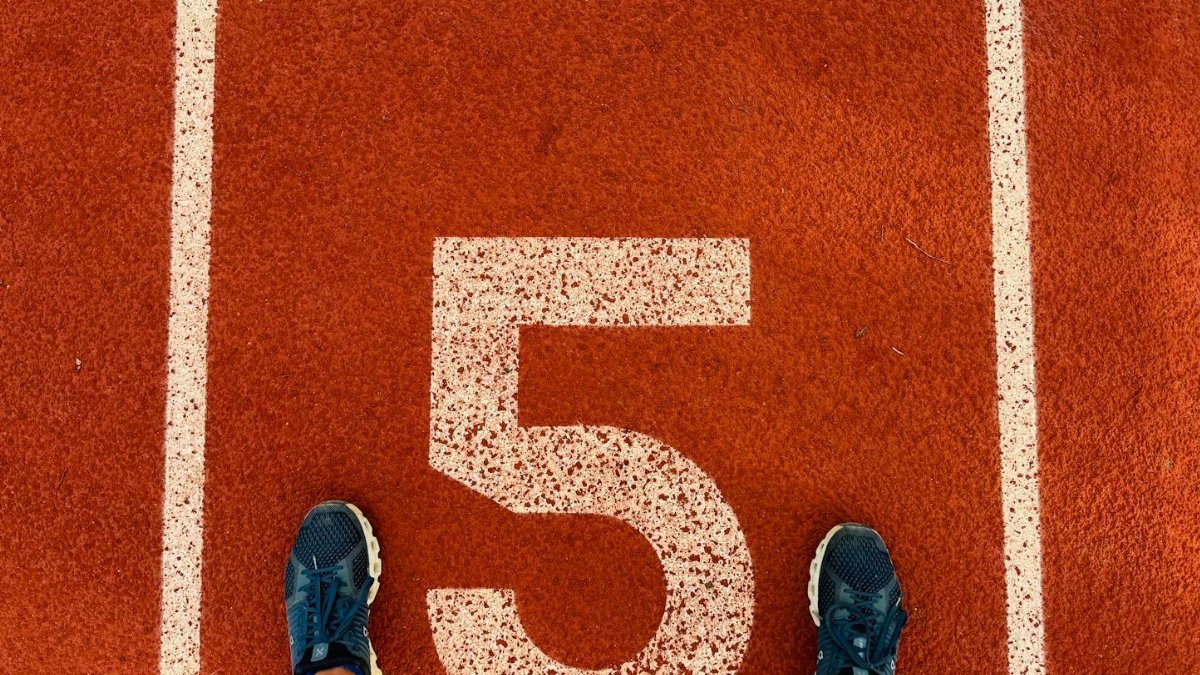 Runner's feet on track lane 5 at the finish line, symbolizing completion and success.