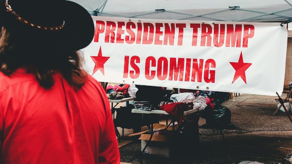 Banner promoting a political event for Donald Trump in Wheeling, WV with market stalls.