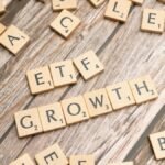 Wooden tiles spelling ETF growth on a wooden surface, symbolizing investment strategy.