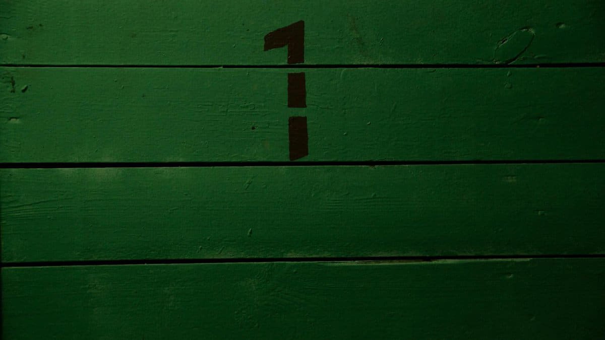 Background of plank wall of green grass color with black simple inscription representing numeral made with template