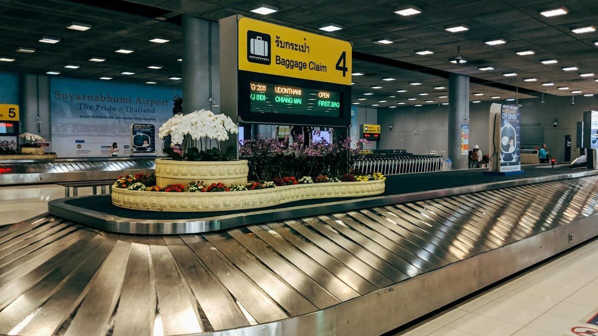 Modern baggage claim area at Suvarnabhumi Airport in Bangkok with luggage carousel and signage.