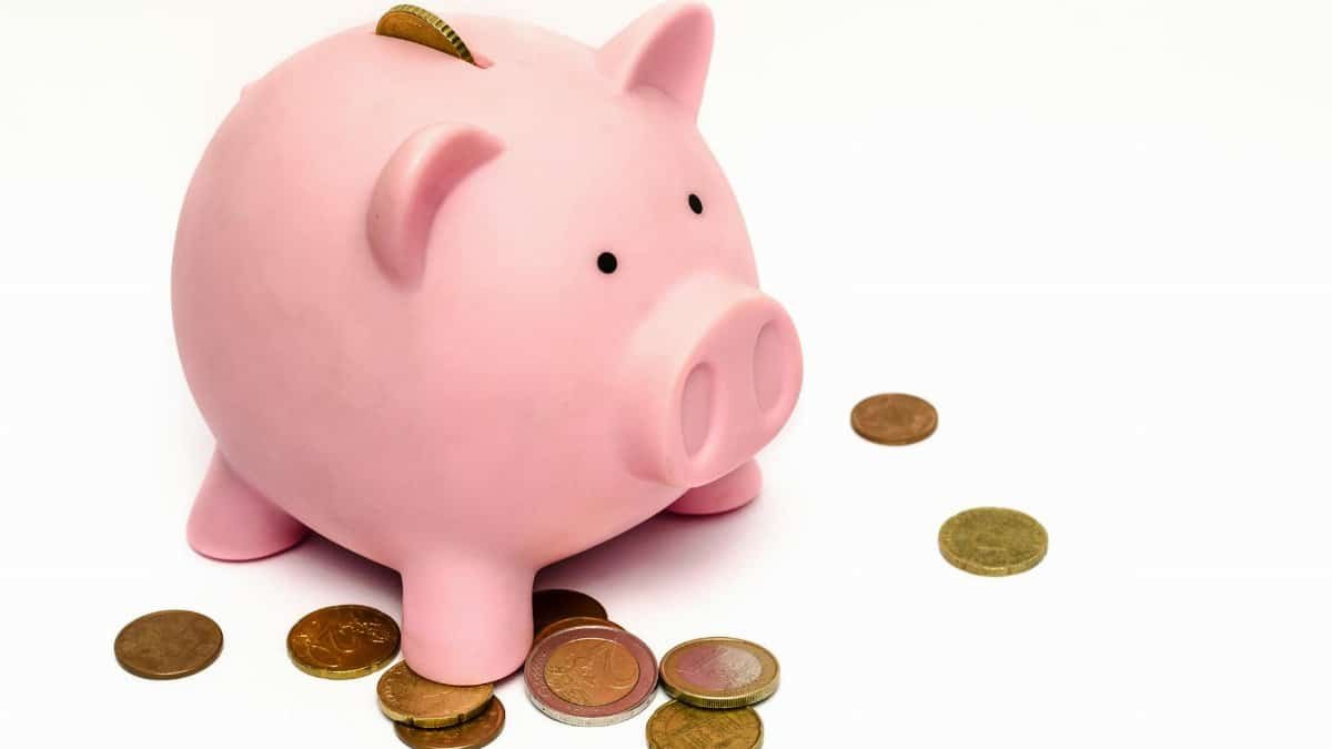 A pink piggy bank surrounded by scattered coins, symbolizing savings and financial investment.