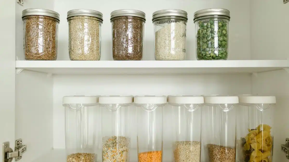 Neatly arranged pantry showcasing grains in glass jars and dry goods in plastic containers.