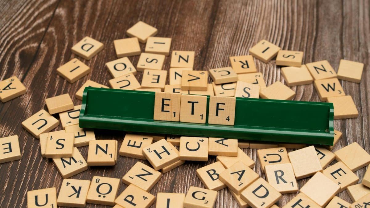 Wooden tiles spelling ETF on a game holder, representing investment themes.