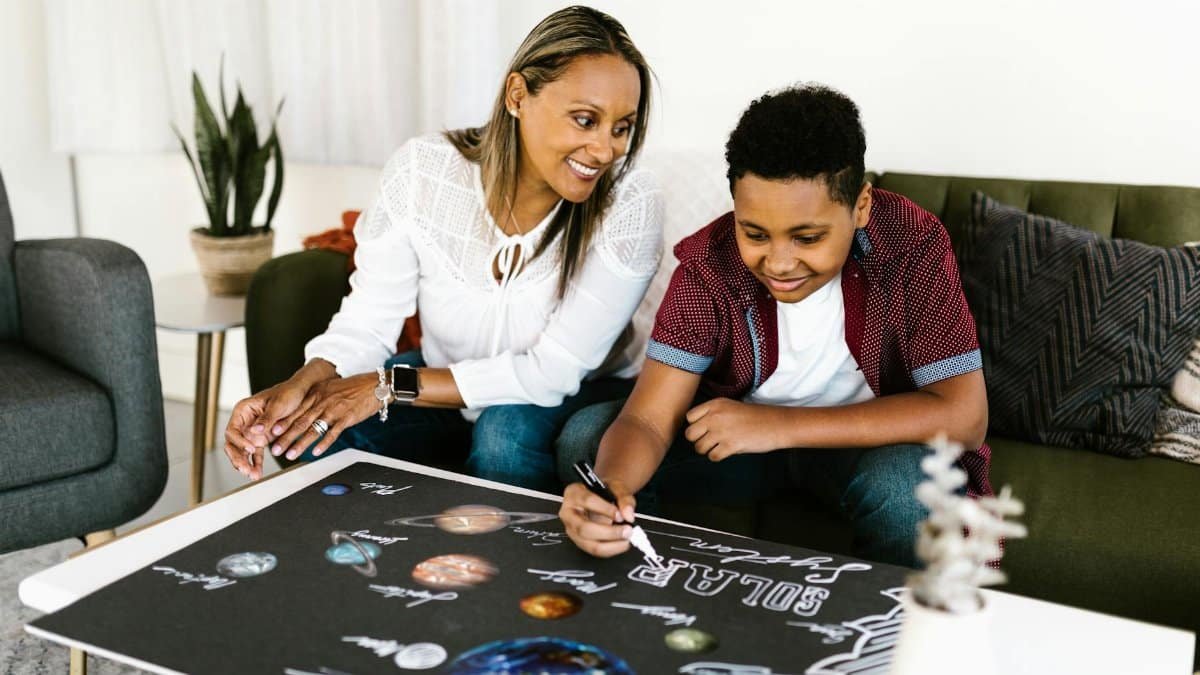 Mother and son engaging in a creative school project about the solar system at home.