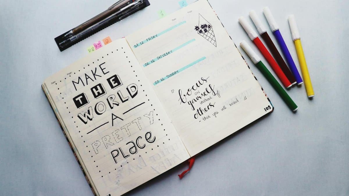 Open bullet journal with quotes and colorful markers for planning and creativity.
