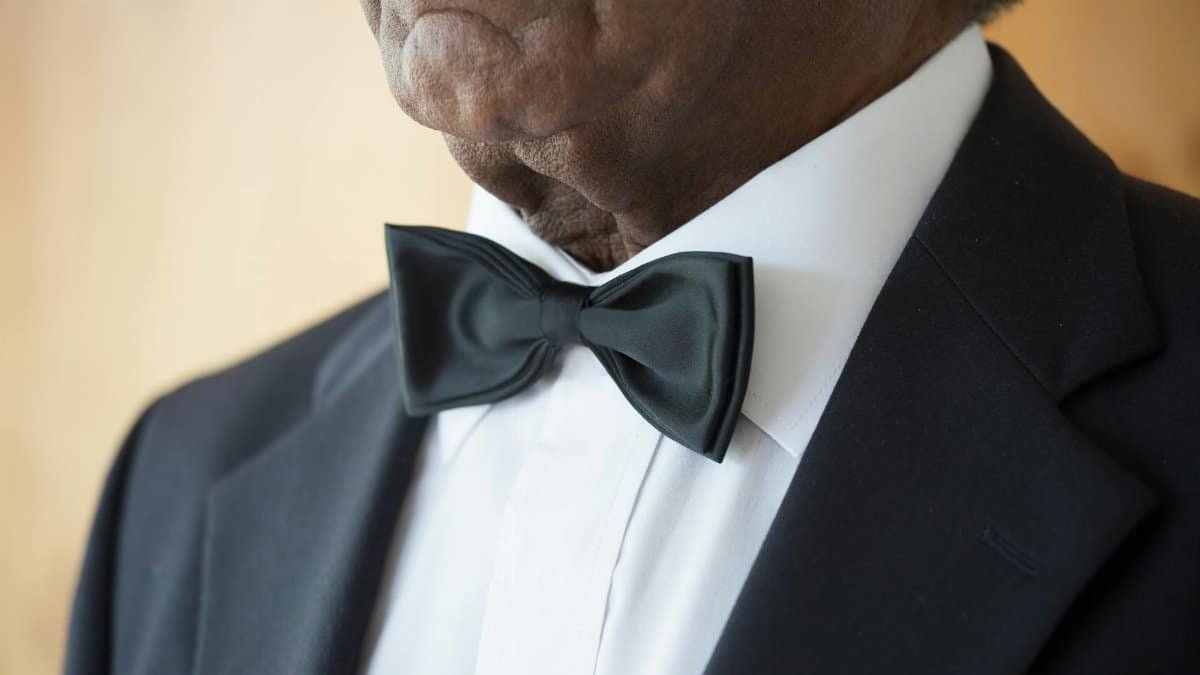 Close-up of an elderly man wearing a classic black tuxedo and bow tie, showcasing style and elegance.