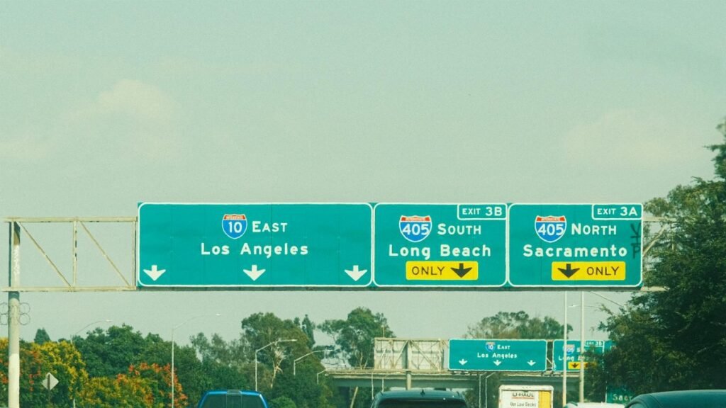 Highway signs with directions to Los Angeles, Long Beach, and Sacramento on a clear day.