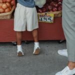 A child and adult picking fresh onions at a local farmers market outdoor stand.