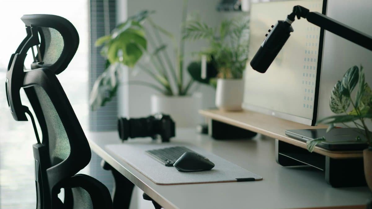 Stylish home office setup with ergonomic chair, plants, and tech accessories creating a modern work environment.