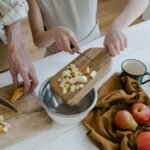 Father and daughter chopping apples and citrus fruits at home for a healthy family meal.