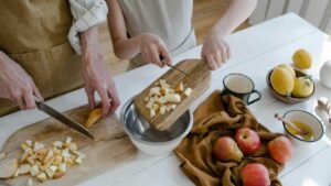 Father and daughter chopping apples and citrus fruits at home for a healthy family meal.