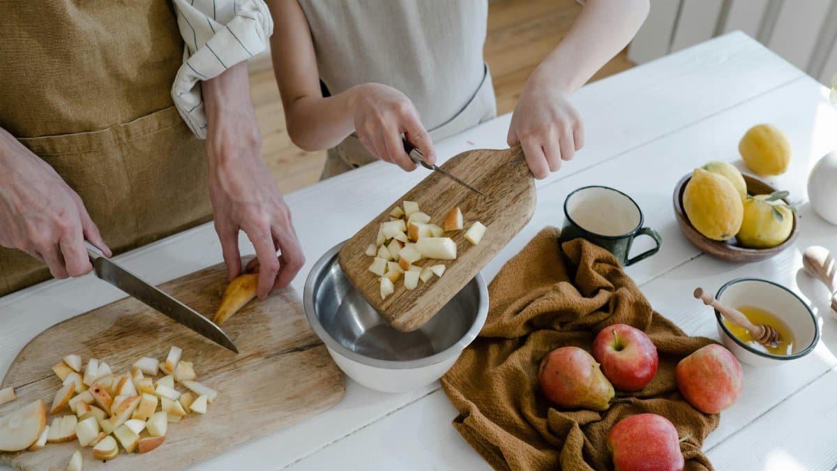 Father and daughter chopping apples and citrus fruits at home for a healthy family meal.