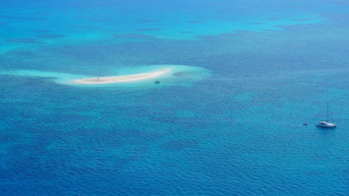 A stunning bird's-eye view of a small island and boat in the blue waters of the Great Barrier Reef.