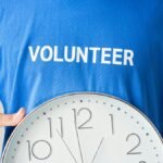 Close-up of a volunteer holding a wall clock, symbolizing time commitment.