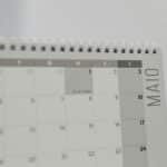 Spiral-bound calendar showing May with focus on weekdays in Portuguese.