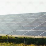 Expansive solar panel array harnessing clean energy in a sunny outdoor field scene.