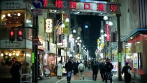 Bustling night scene in Minato City, Tokyo with people, shops, and illuminated street signs.