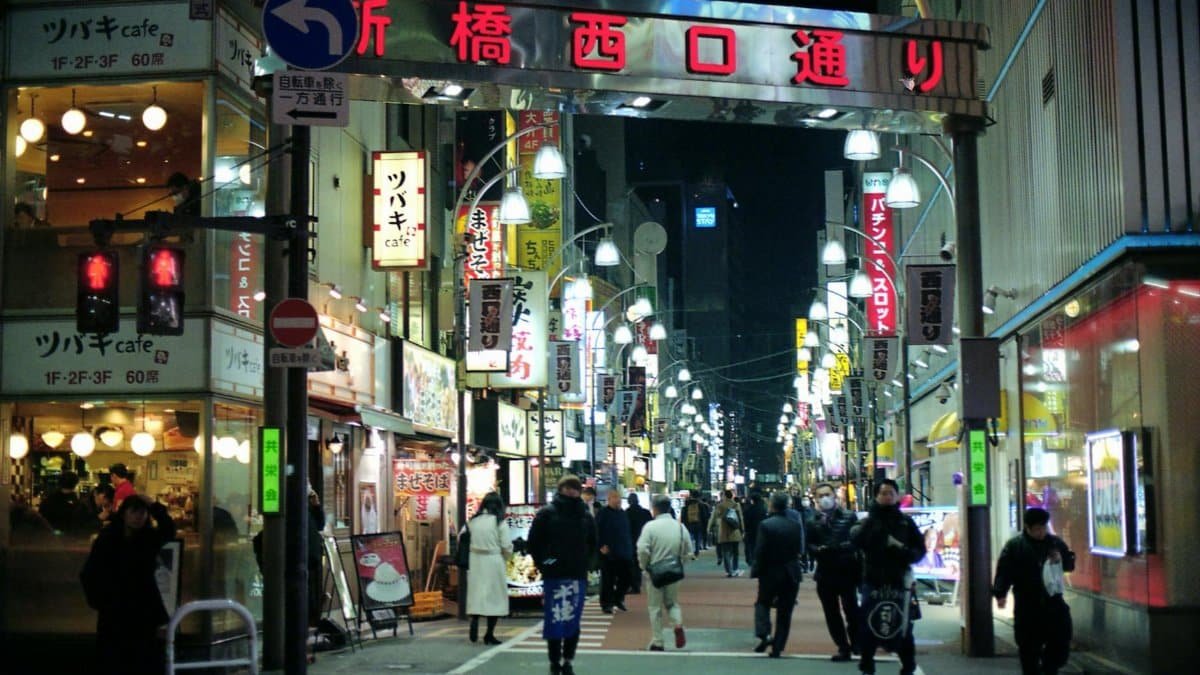 Bustling night scene in Minato City, Tokyo with people, shops, and illuminated street signs.