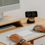 A clean and modern desk setup featuring a computer, clock, and accessories in a home office.