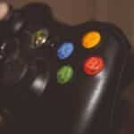 Close-up image of a hand holding a gaming controller with colorful buttons.