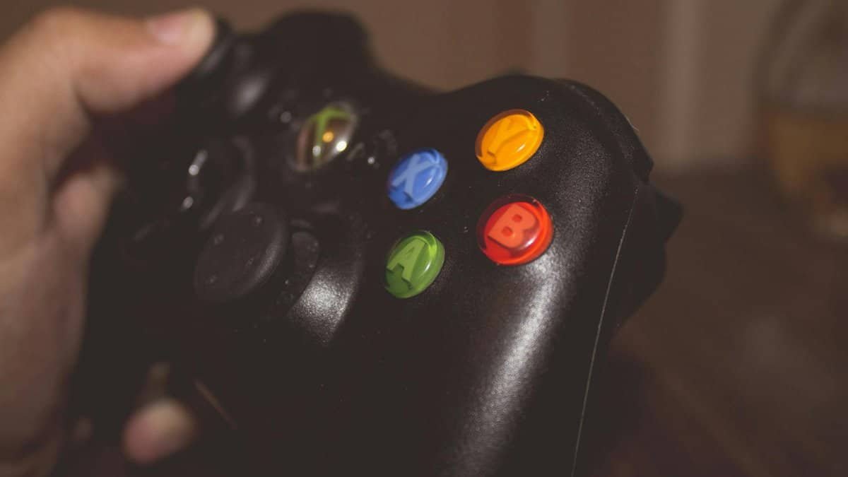 Close-up image of a hand holding a gaming controller with colorful buttons.