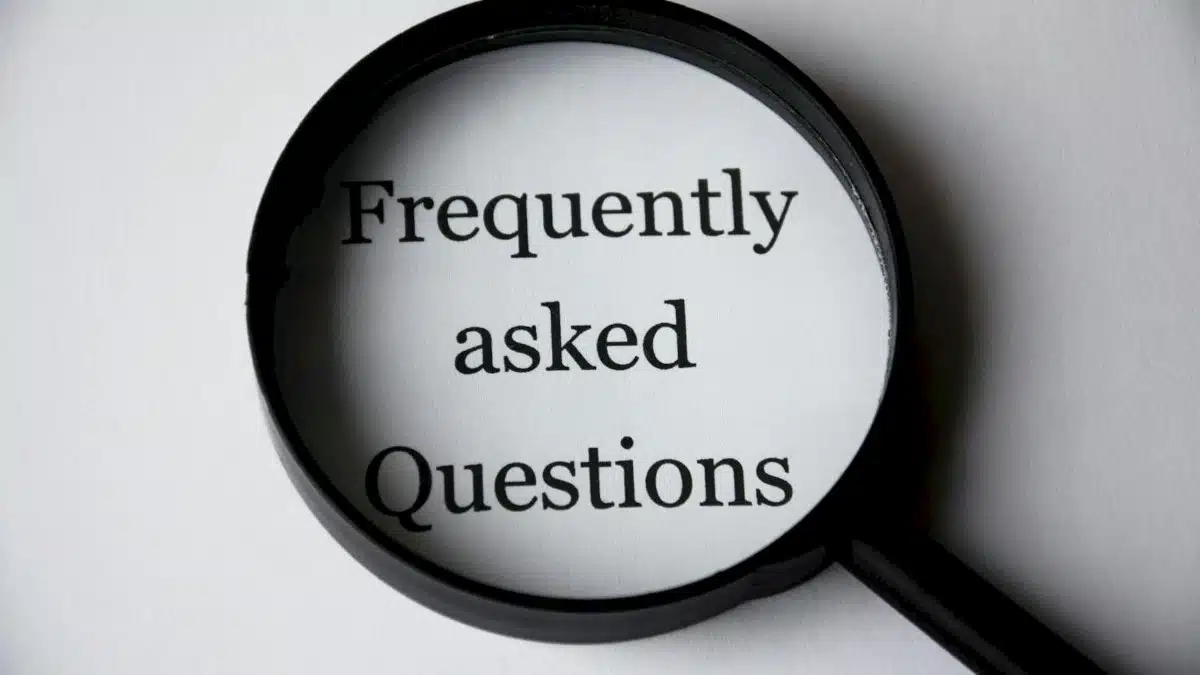 Close-up of a magnifying glass focusing on the phrase 'Frequently Asked Questions'.