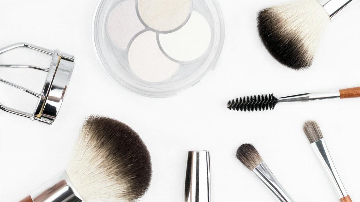Flat lay of various makeup brushes and tools on a white background.