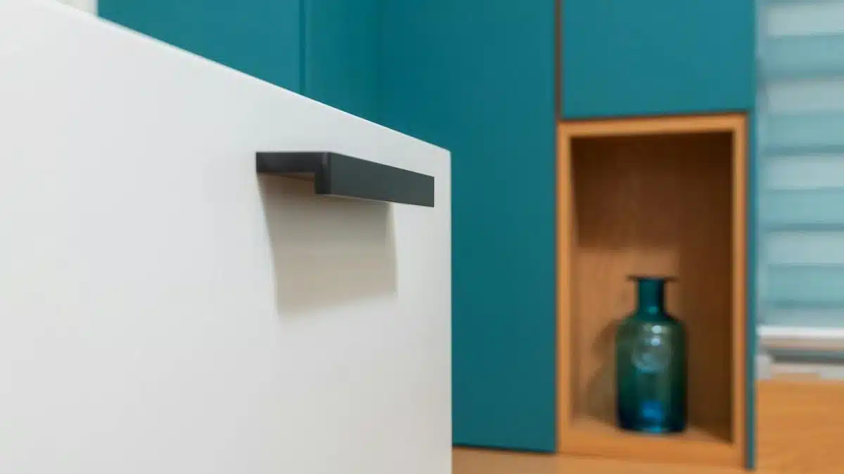Sleek minimalist kitchen design with teal cabinets and decorative vase.