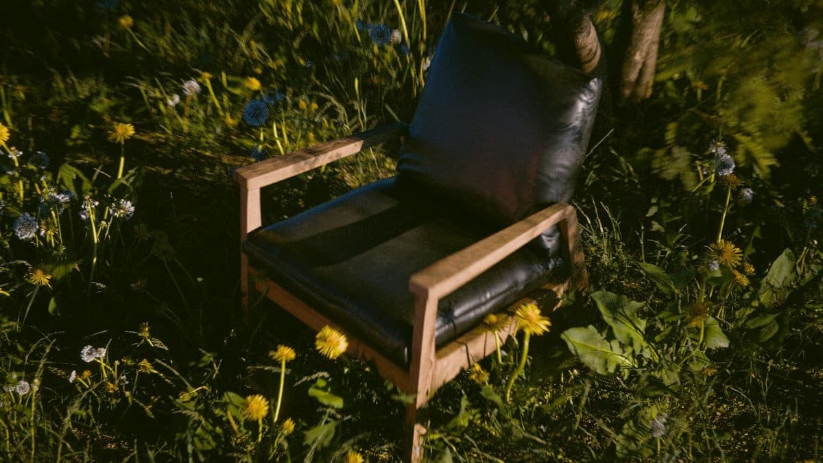 Cozy black chair on wooden frame amidst blooming meadow flowers, offering a serene outdoor retreat.