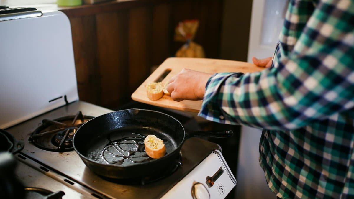 Person cooking with skillet on stove, preparing a delicious meal. Cozy kitchen atmosphere.