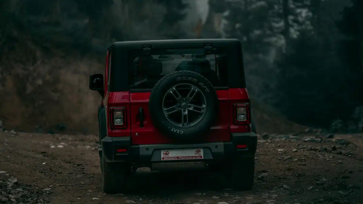 A red off-road vehicle travels down a rugged dirt path surrounded by forest scenery, perfect for adventure seekers.