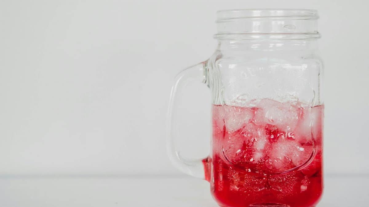 Refreshing red drink with ice in a mason jar, perfect for summer.