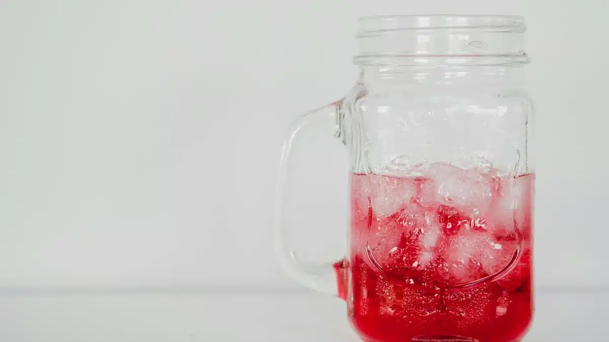 Refreshing red drink with ice in a mason jar, perfect for summer.