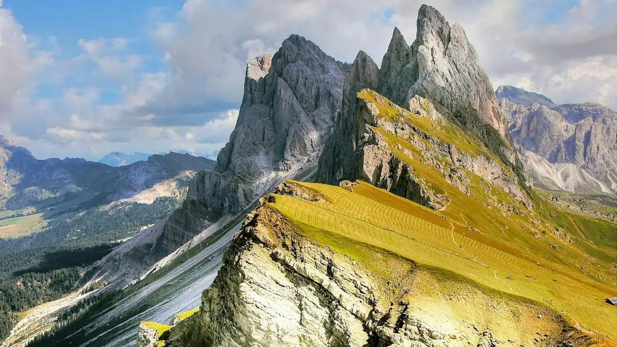A breathtaking view of jagged mountain peaks and lush valleys under a vibrant blue sky.