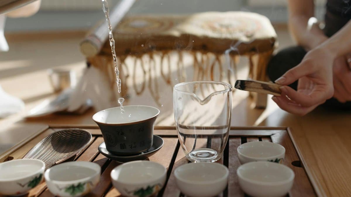 A serene tea ceremony featuring steaming hot water and a Palo Santo ritual on a wooden tray.