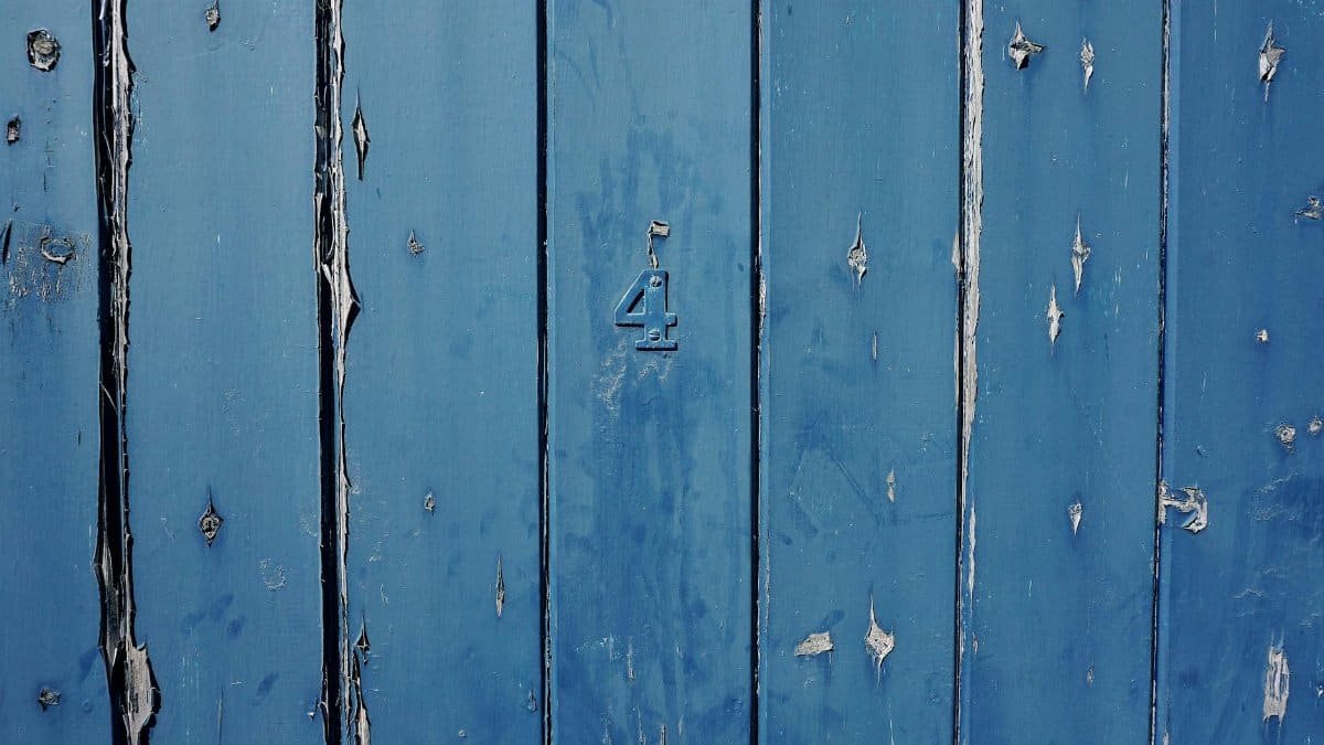 A close-up of a weathered blue wooden door featuring the number 4, showcasing texture and rustic charm.