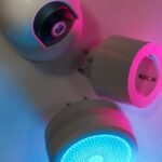 Three smart home devices illuminated by blue and pink neon lights, showcasing technology innovation.
