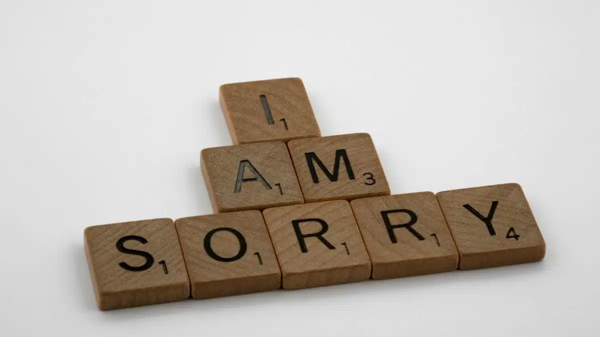 Wooden Scrabble tiles arranged to say 'I Am Sorry' on a clean white background, conveying a message of apology.